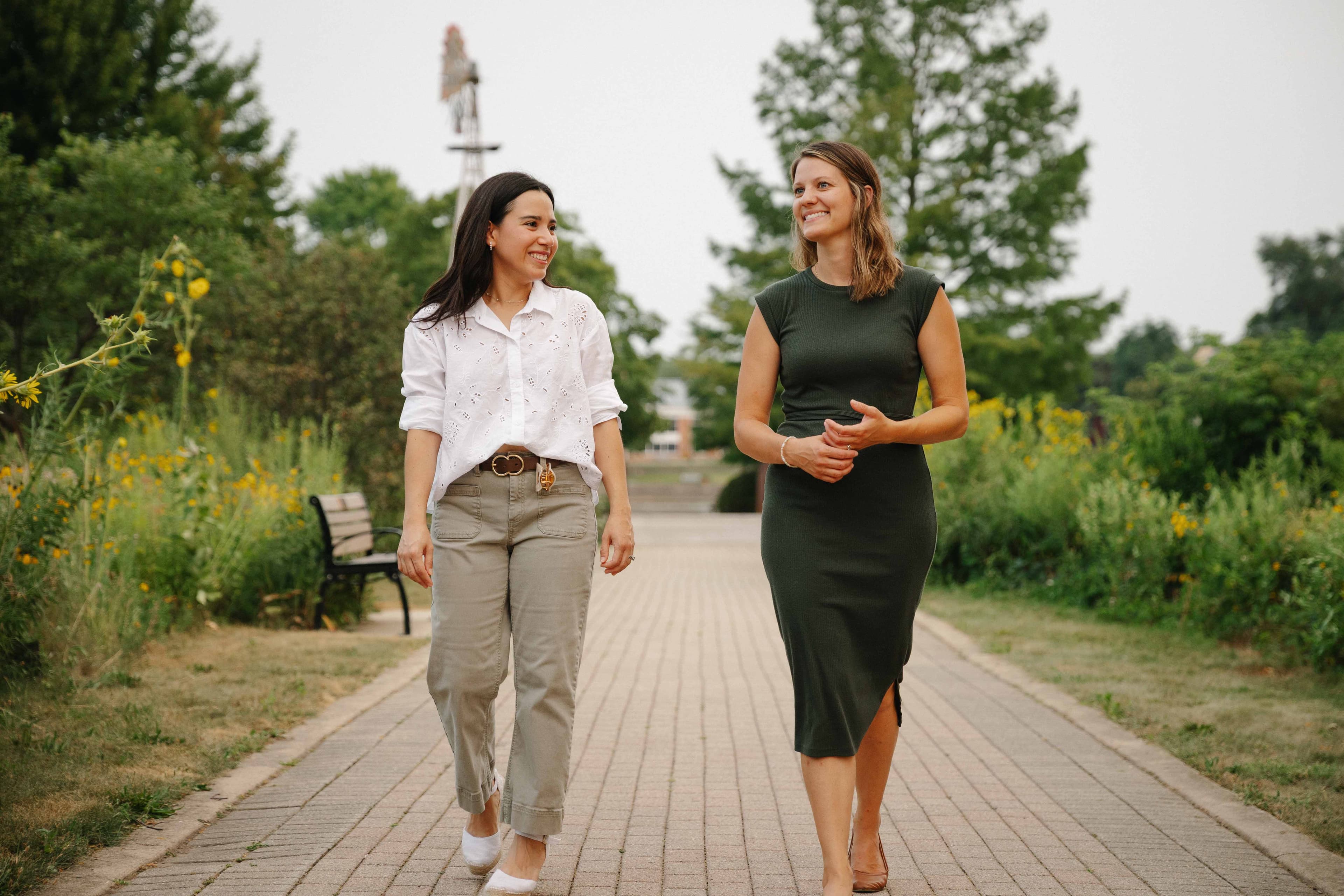 Maria and Sarah walking together on the path outside the Batavia office
