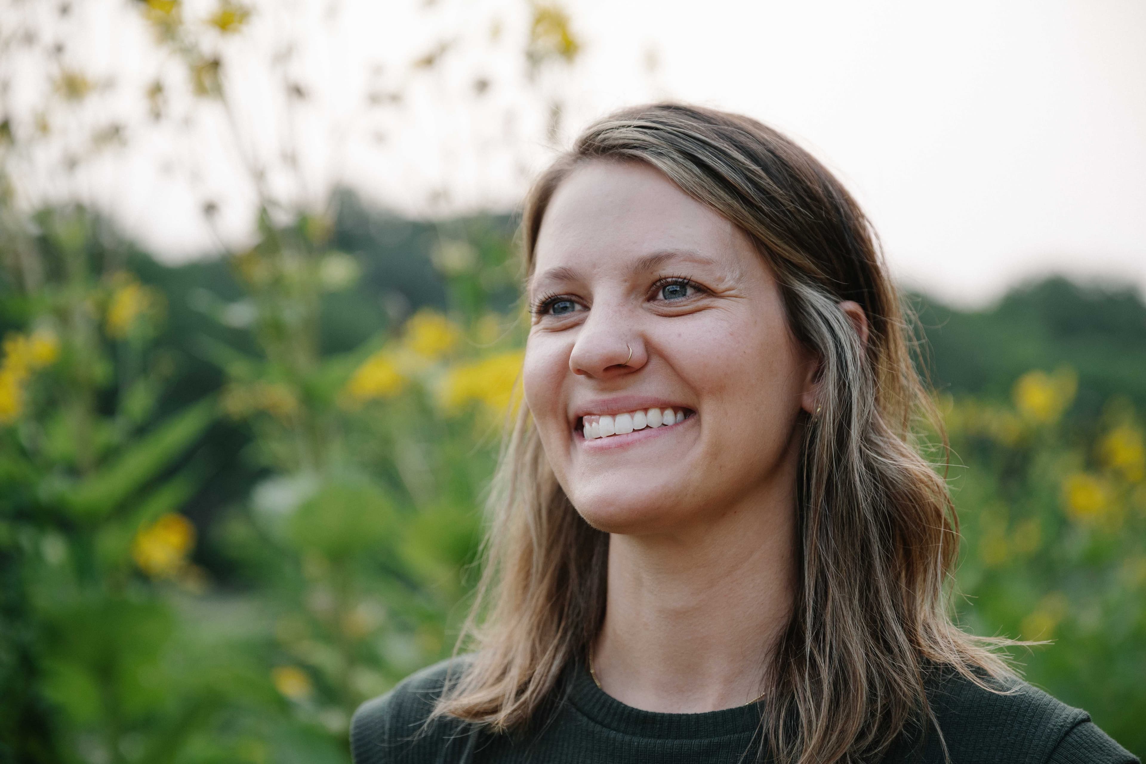 Sarah Stetina, MSN, CNM, smiling outdoors among the prairie wildflowers